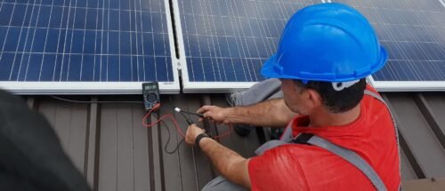 Installateur de panneaux solaires contrôlant le bon fonctionnement d'un module photovoltaïque à l'aide d'un multimètre