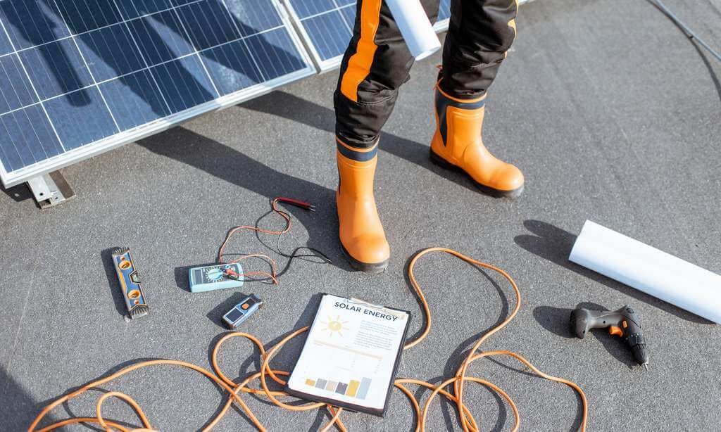 Installateur photovoltaïque avec outil posés sur la toiture-terrasse recevant les panneaux solaires
