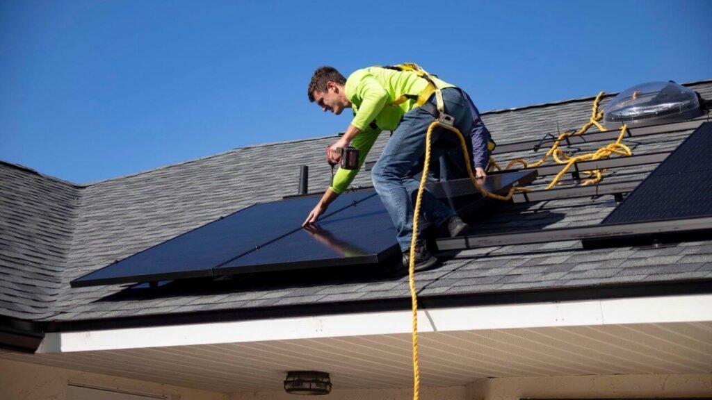 2 installateurs sur le toit d'une maison qui fixent un panneau solaire